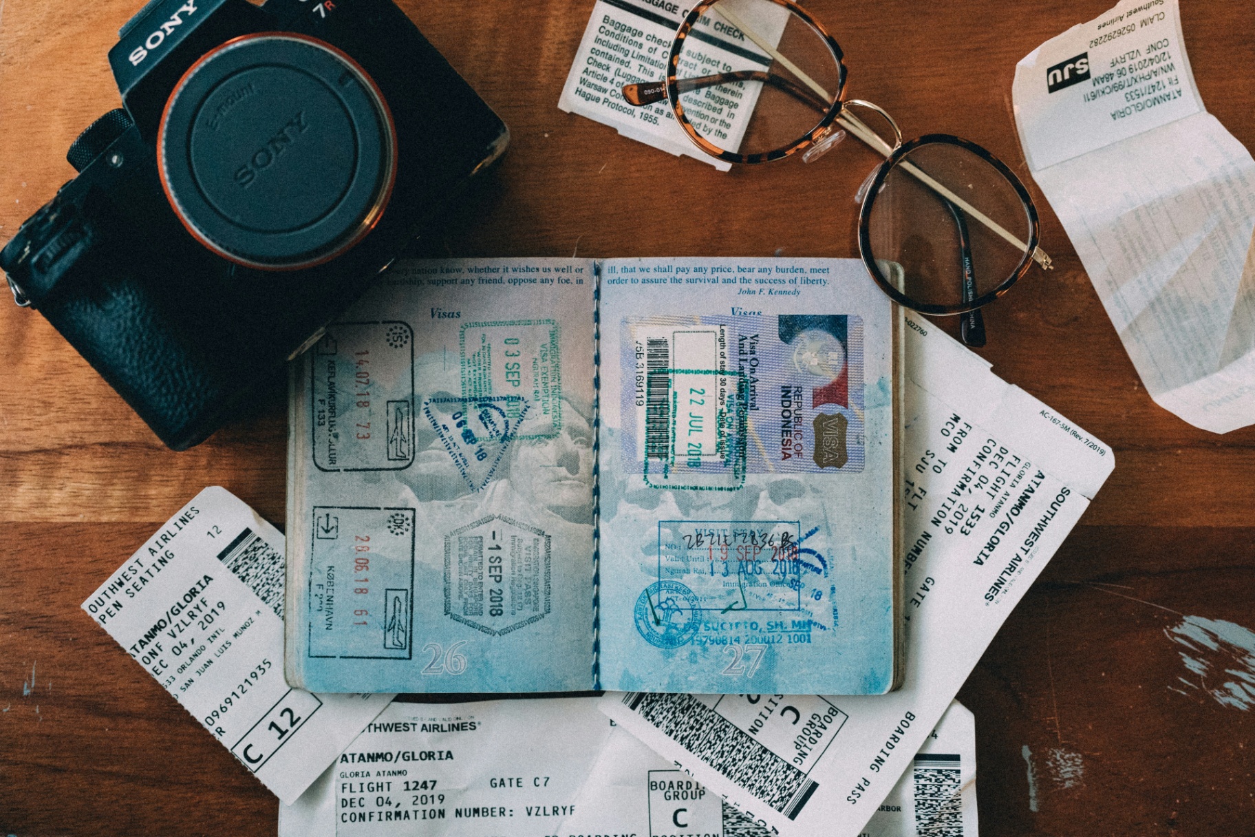 Passport with travel stamps, boarding passes, and camera on a desk